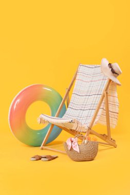 Sarı arka planda plaj aksesuarları olan bir iskemle.