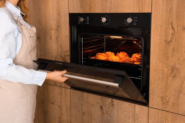 Kadın mutfakta çöreklerle fırın açıyor.