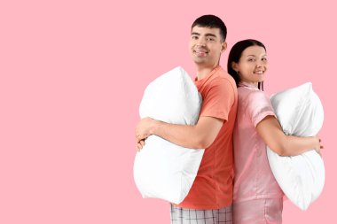 Pembe arka planda yastıkları olan genç çift.