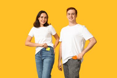 Sarı arka planda prezervatifleri olan genç bir çift. Güvenli seks konsepti