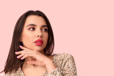 Pembe arka planda şık makyajlı güzel bir genç kadın.