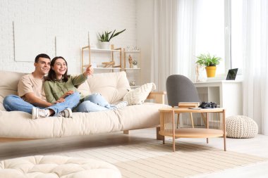 Genç çift evde kanepede televizyon izlerken