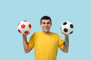 Mavi arka planda futbol topları olan genç bir adam.