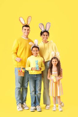 Tavşan kulaklı mutlu bir aile Paskalya tavşanları ve sarı arka planda yumurtalar.