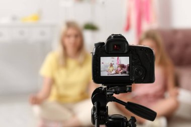 Güzel kadın blogcu ve kızı evde kamera önünde video kaydediyor.