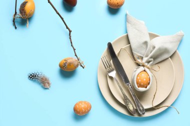 Mavi arka planda Paskalya yumurtaları ve ağaç dallarıyla güzel bir masa.