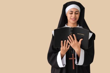 Genç rahibe bej arka planda İncil okuyor.