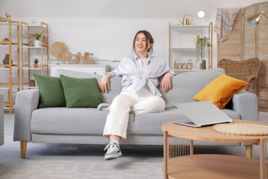 Oturma odasındaki kanepede dinlenen güzel genç bayan.