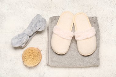 Beyaz terlikler, havlu ve beyaz arka planda vücut masajı fırçası. Üst görünüm