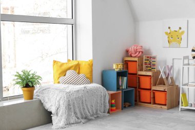 Modern çocuk odasının penceresinin yanındaki gri ekose yastıklarda