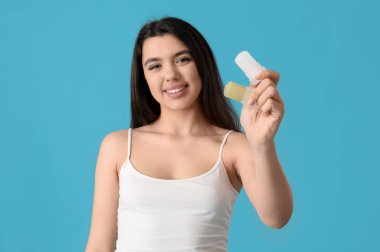 Happy smiling young woman with crystal deodorants on blue background clipart