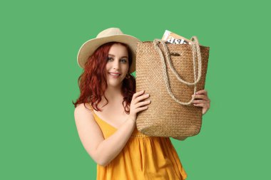Yeşil arka planda şık hasır çantalı güzel, genç ve mutlu bir kadın.