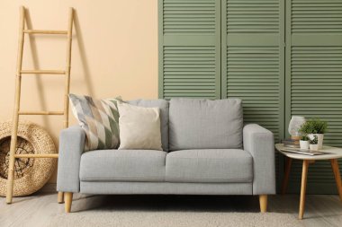 Gri kanepeli, masalı ve katlanır perdeli oturma odasının içi.