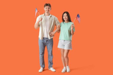 Turuncu arka planda ABD bayrakları olan genç çift.