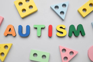 Kelime AUTISM ve gri arka planda eğitici oyuncaklar. Üst görünüm