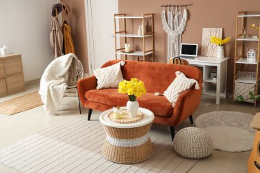 Kahverengi kanepesi, sehpası ve narsisli çiçekleri olan güzel bir oturma odası.