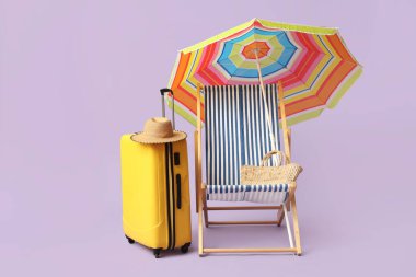 Renkli şemsiyeli çizgili güverte sandalyesi ve leylak arka planda valizi.