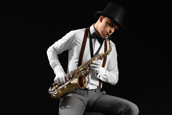 Мужчина играет на саксофоне на черном фоне