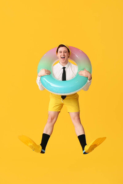 Офисный работник с надувным кольцом и ластами мечтает об отпуске на желтом фоне