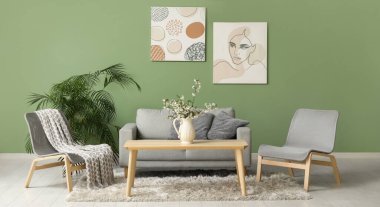 Gri kanepe, sandalyeler ve vazo. Şık bir oturma odasının içindeki masanın üzerinde çiçek açan ağaç dalları var.