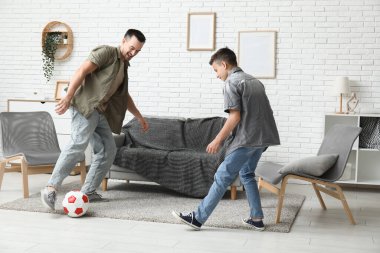 Babası ve küçük oğlu evde futbol oynuyorlar.