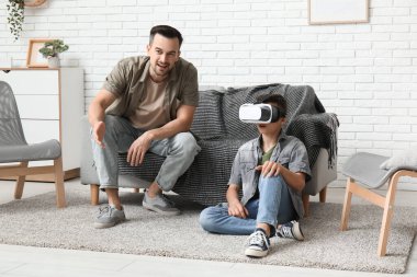 Babası ve VR gözlüklü küçük oğlu evde eğleniyorlar.