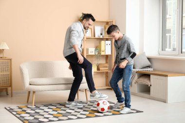 Babası ve küçük oğlu evde futbol oynuyorlar.