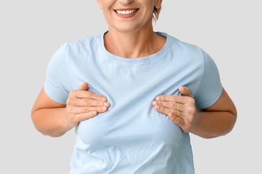 Olgun bir kadın göğsünü arka planda kontrol ediyor, yakın plan. Kanser farkındalığı kavramı