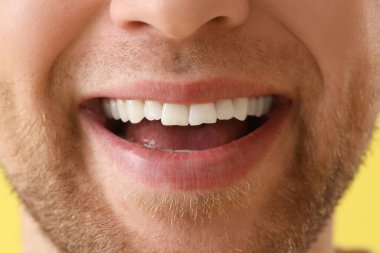 Sarı arka planda gülümseyen genç adam, yakın plan.