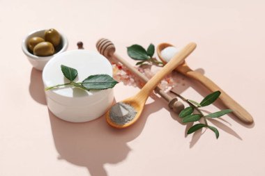 Doğal yüz kremi kavanozu, bej arka planda deniz tuzu ve zeytin içeren kompozisyon
