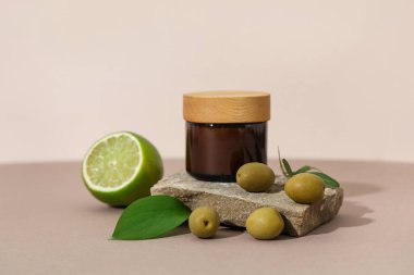 Bej arka planda doğal kozmetik ürünü, limon ve zeytin kavanozu