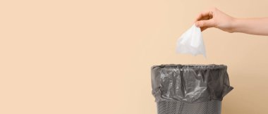 Kadın el, bej arka planda çöp kutusuna mendil atıyor ve metin için yer var.