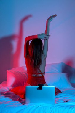 Laptoplu çekici genç bir kadın gece yatak odasında sanal seks yapıyor.