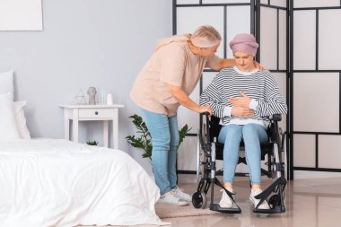 Tekerlekli sandalyedeki kemoterapiden sonra annesi evde olan genç bir kadın. Mide kanseri kavramı