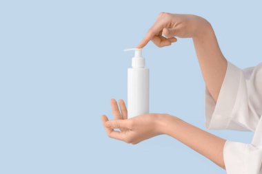 Renkli arka planda krem şişesi olan kadın elleri, yakın plan.