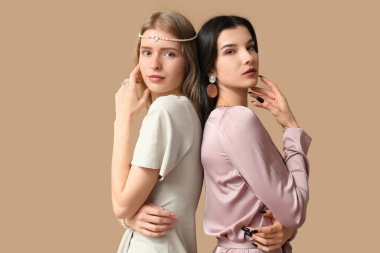 Kahverengi arka planda farklı takılara sahip güzel genç kadınlar.