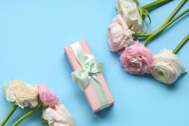 Mavi arka planda hediye kutusu olan güzel ranunculus çiçekleri