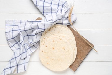 Tahta tahta tahta, beyaz ahşap arka planda taze lavaş ve havlu.