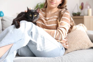 Oturma odasında tatlı siyah kediyle oturan bir kadın, yakın plan.