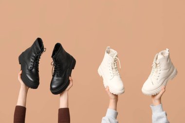 Kahverengi arka planda farklı stil deri çizmeleri olan kadın elleri.