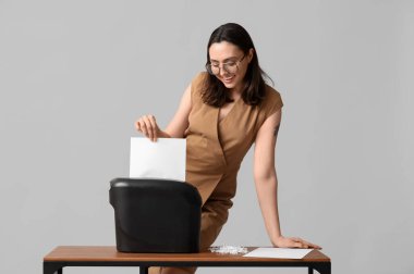 Sekreter arka planda belgeyi kağıt öğütücüsünde imha ediyor