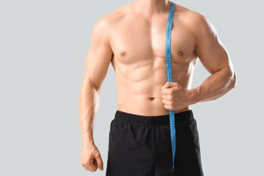 Açık arkaplanda mezura olan erkek vücut geliştirici, yakın plan.