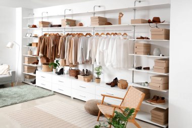 Modern giyinme odasının içinde gardırop kutuları, şık kıyafetler ve aksesuarlar var.