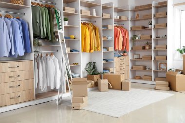 Modern giyinme odasının içinde gardırop kutuları, şık kıyafetler ve aksesuarlar var.