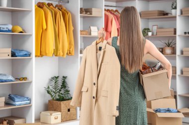 Soyunma odasında kostüm kutusu ve şık ceketi olan güzel genç bir kadın.