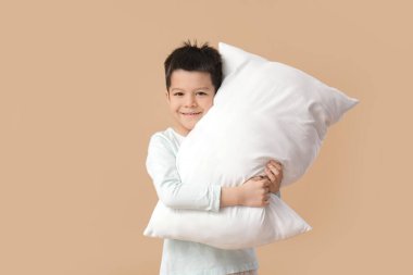 Bej arka planda yastıklı pijamalı şirin Asyalı çocuk.