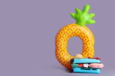 Plaj aksesuarlarıyla dolu bavul ve renk arkaplanında şişirilebilir yüzük