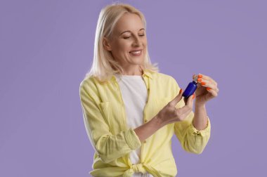 Arkaplanda bir şişe CBD yağı olan olgun bir kadın.