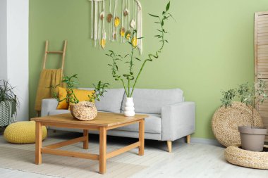 Kahve masası ve kanepenin üzerinde bambu sapları olan yeşil oturma odasının modern iç mekanı.