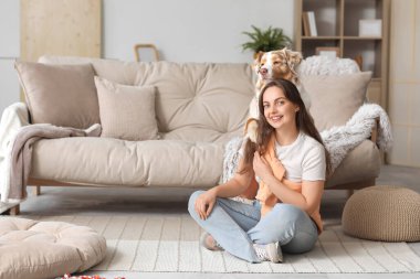 Yumuşak tüylü Avustralya çoban köpeği olan bir kadın oturma odasında.